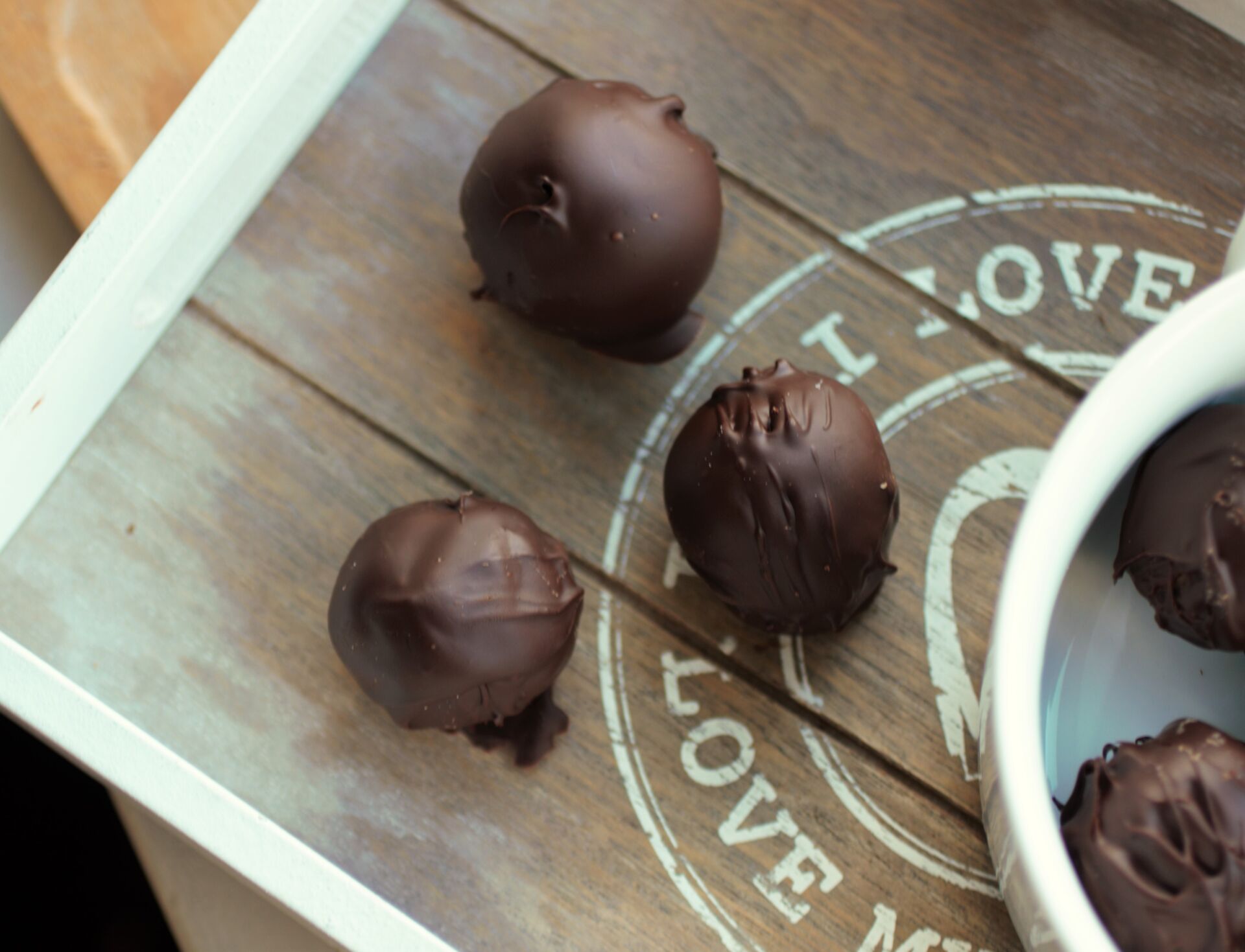 3 vegan oreo cheesecake bites on a wooden tray, next to a bowl of oreo cheesecake bites