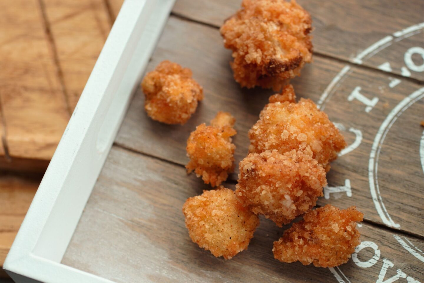 close up of pieces of popcorn cauliflower on a wooden tray