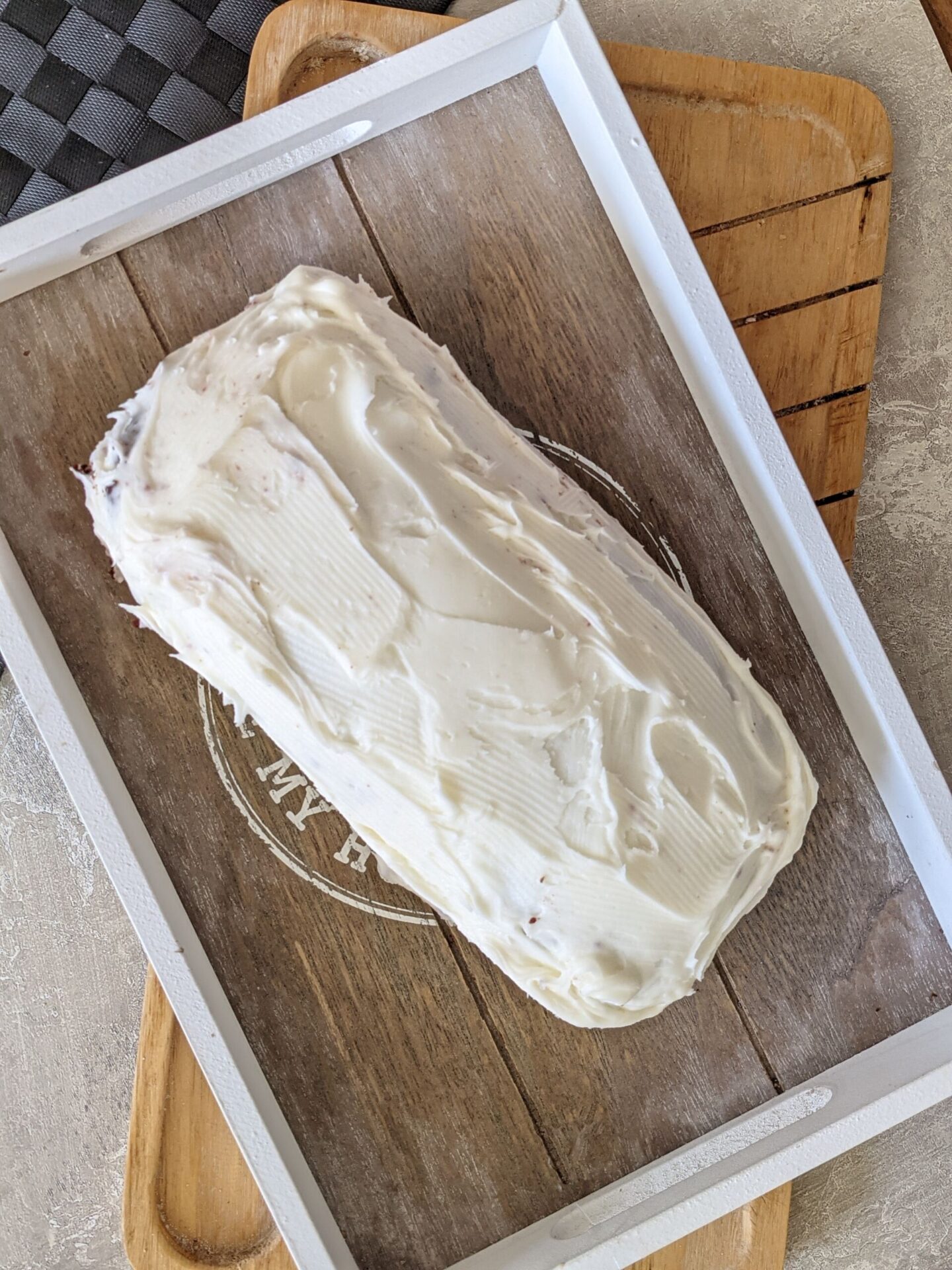the red velvet loaf, frosted, placed on a grey wooden tray, shot from above