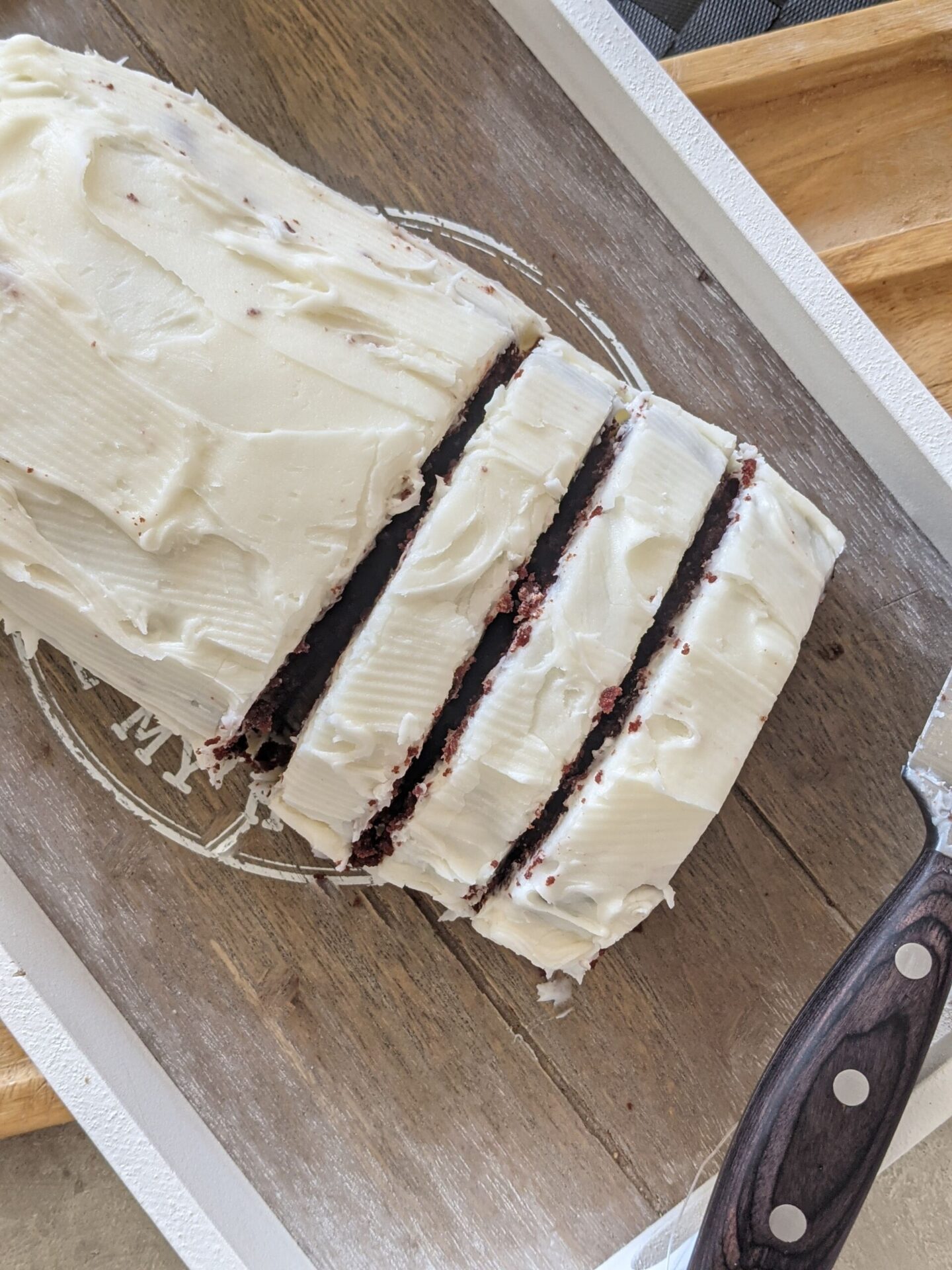 red velvet loaf recipe, with a few slices cut, on a grey wooden board with the knife placed over the edge. Shot from above.