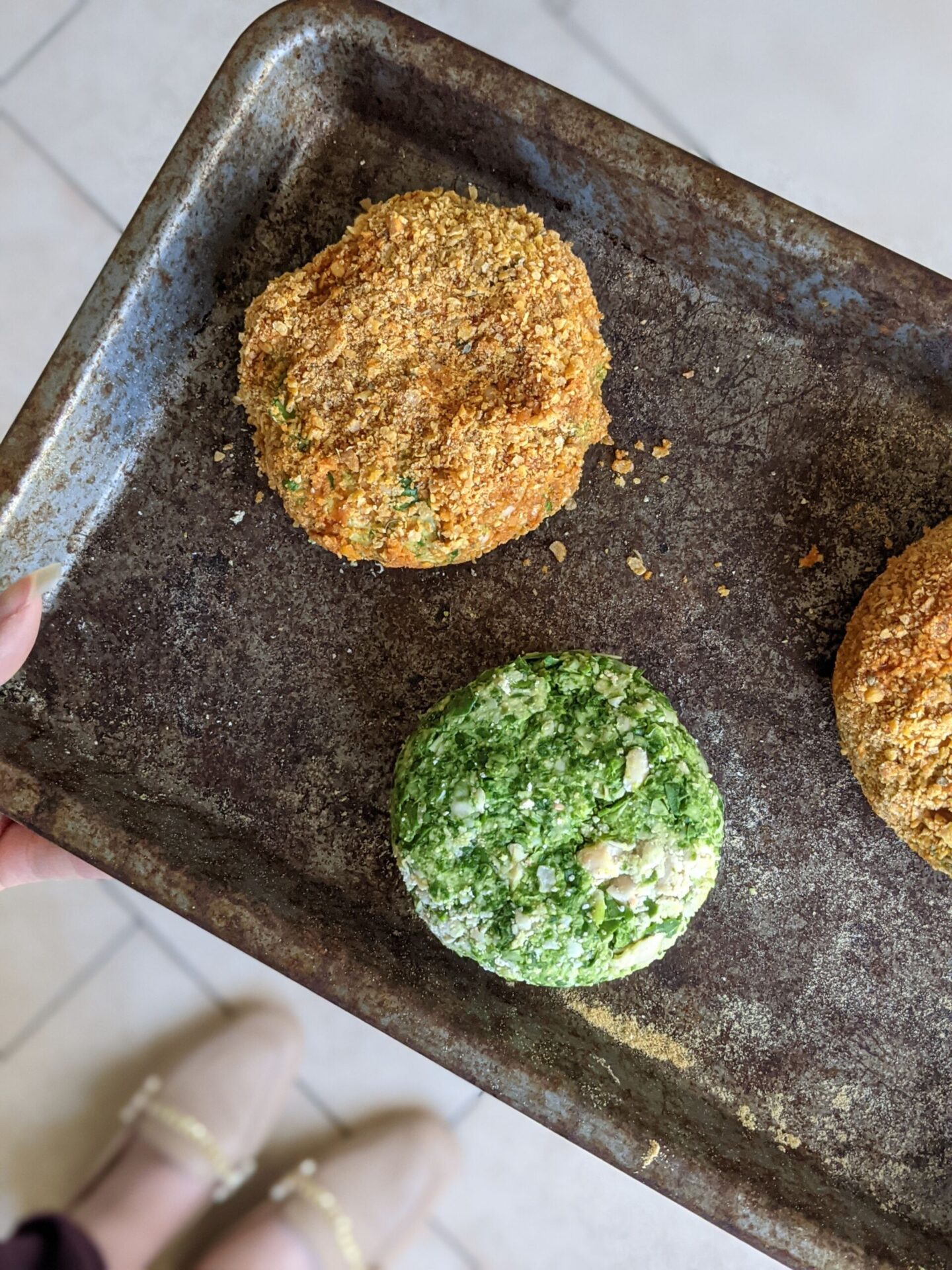 spinach burgers recipe - a baking tray with a breaded and plain burger on