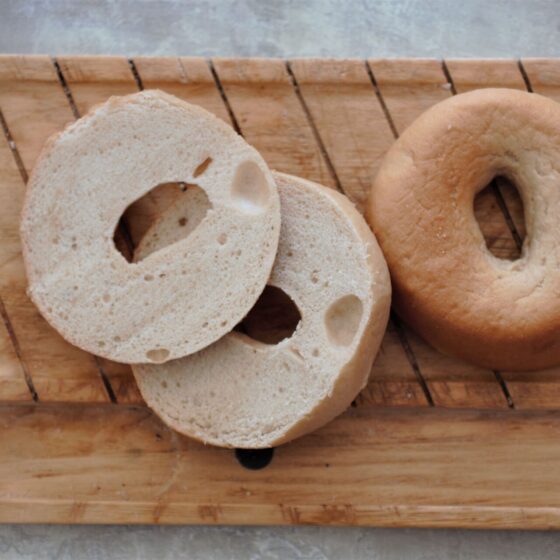 a wooden tray with two gluten free bagels placed on it