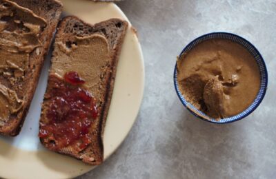 a pot of nut butter next to a slice of nut butter on toast