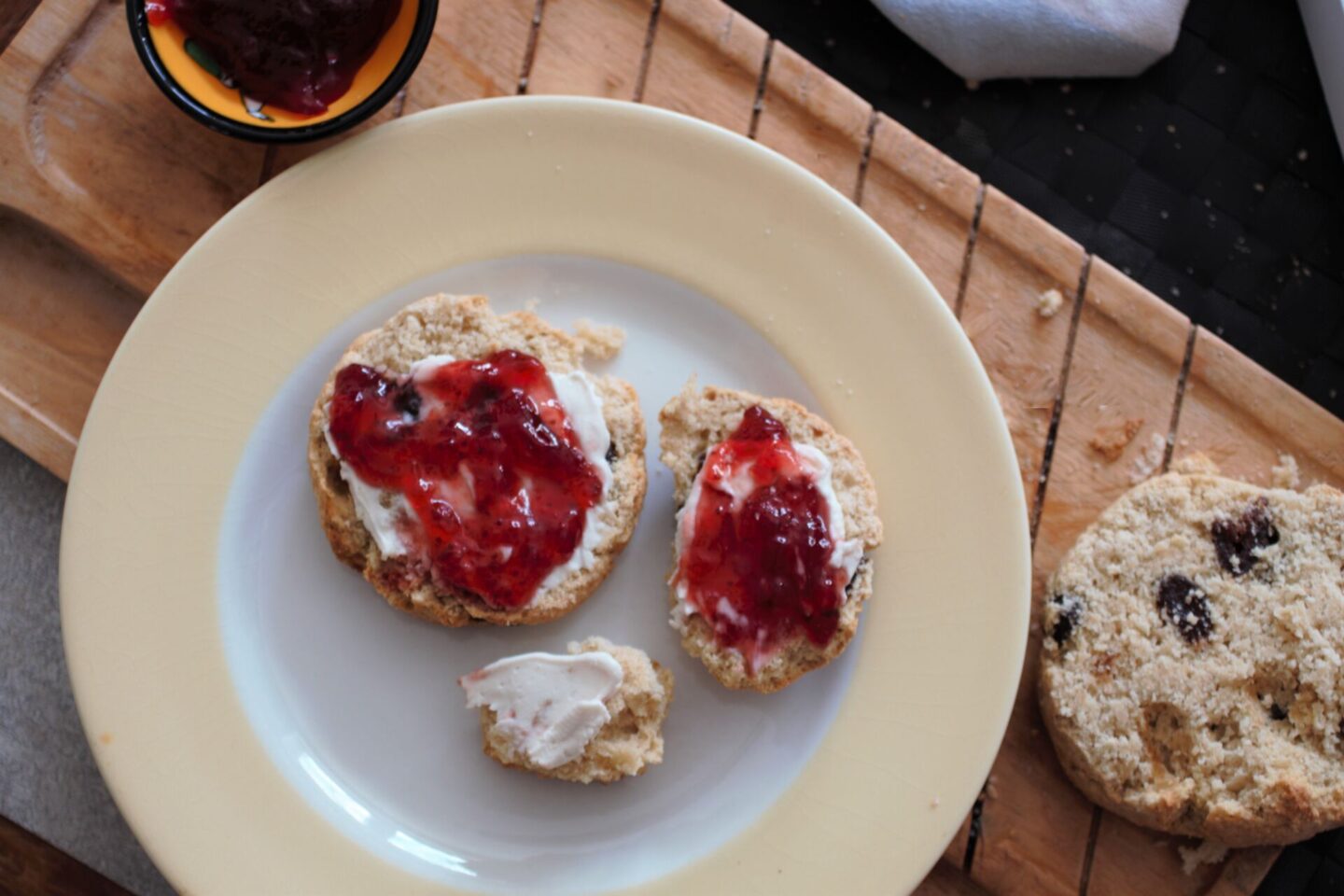a sliced strawberry scone on a plate, topped with jam and Nush cream cheese