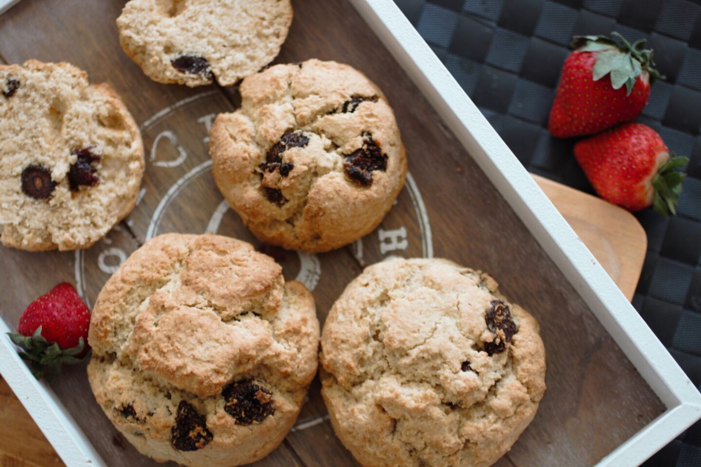 a tray of strawberry scones with a few strawberries scattered around the edge