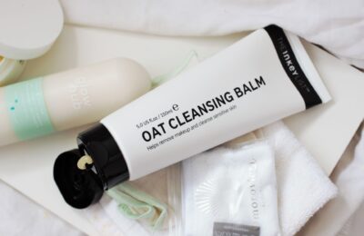 the inkey list oat cleansing balm tube, shot from above with some cloths placed next to it