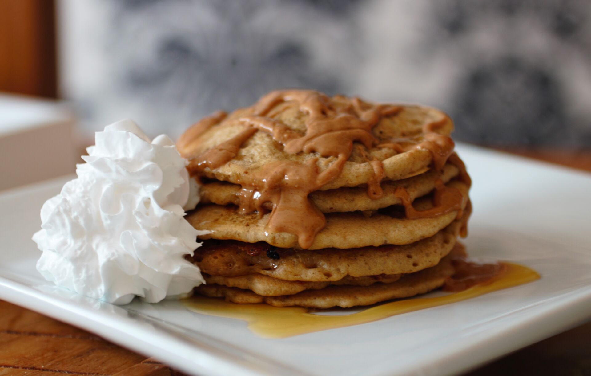 birthday breakfast - a stack of pancakes on a white plate with peanut butter and syrup on them