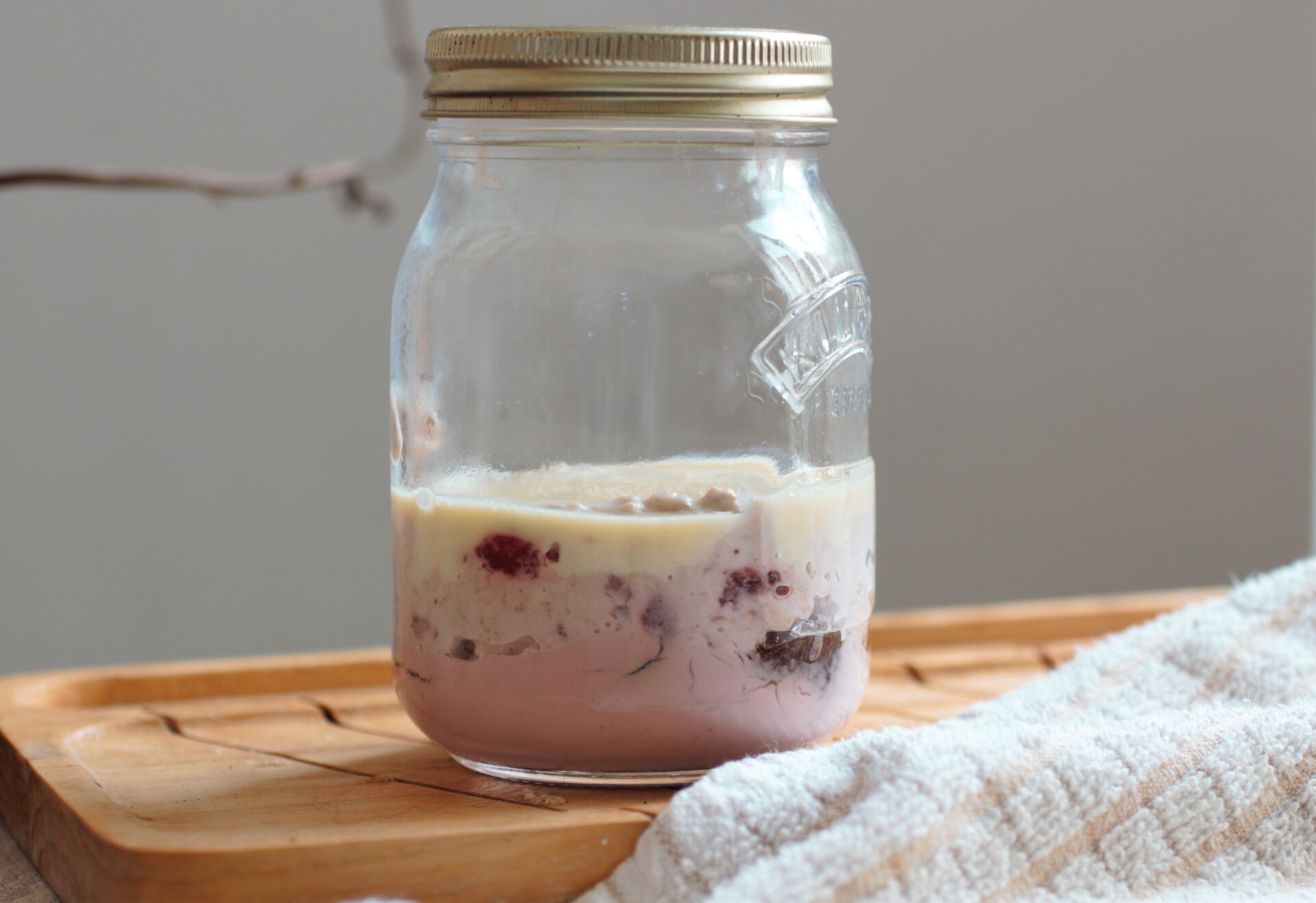 kilner jar of strawberry cheesecake overnight oats recipe placed on a wooden board