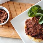 red wine lentil paste on garlic bread, placed on a white plate on a wooden board