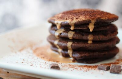 a stack of mocha pancakes drizzled in peanut butter