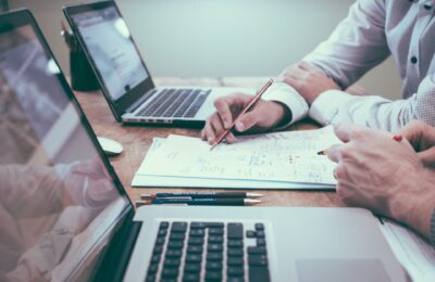 Is an SMSF right for you - a table with someone working on some papers, surrounded by laptops