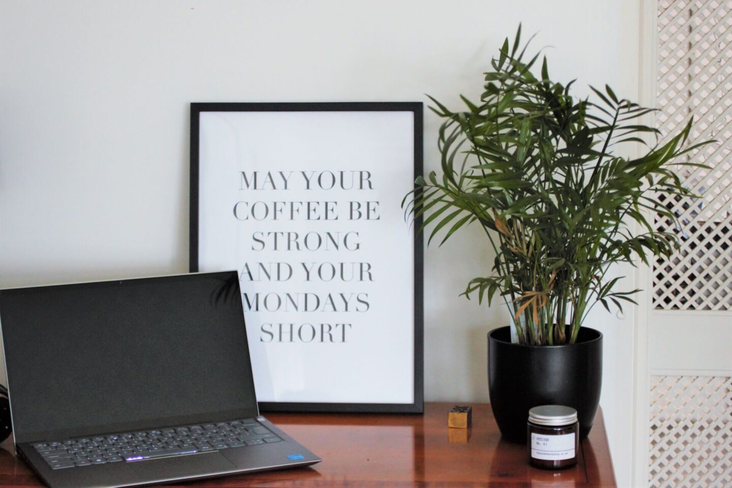 a black and white quote print placed on top of a side table, next to a laptop/ work setup