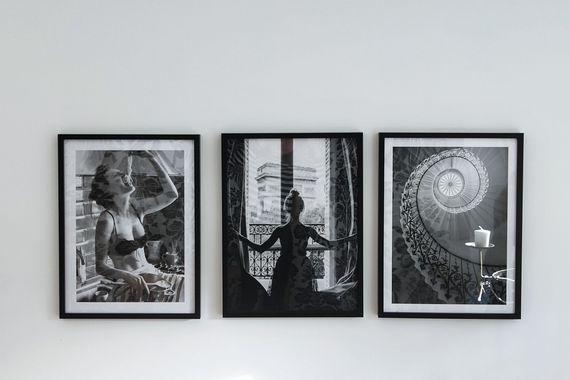 three black & white prints on a white wall, in black wooden frames