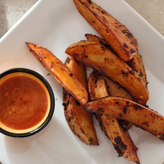 Chipotle Fries recipe on a square white plate, placed next to a pot of hot sauce