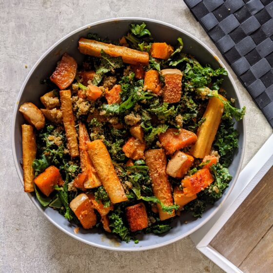 a bowl of fall vegetable salad placed next to a wooden tray