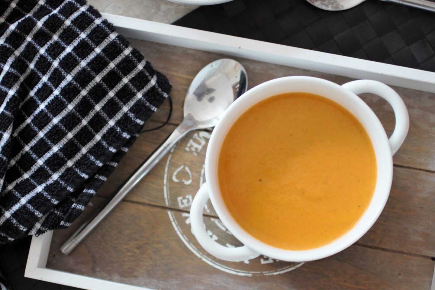 smoked carrot soup recipe in a white bowl placed on a grey wooden tray