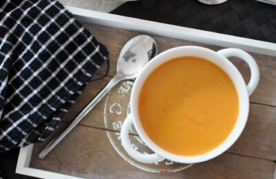 smoked carrot soup recipe in a white bowl placed on a grey wooden tray