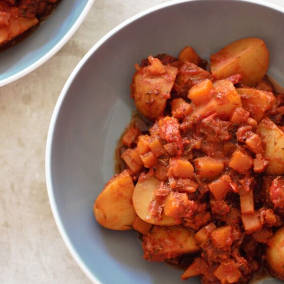 bowl of red wine potato casserole against a grey marl background