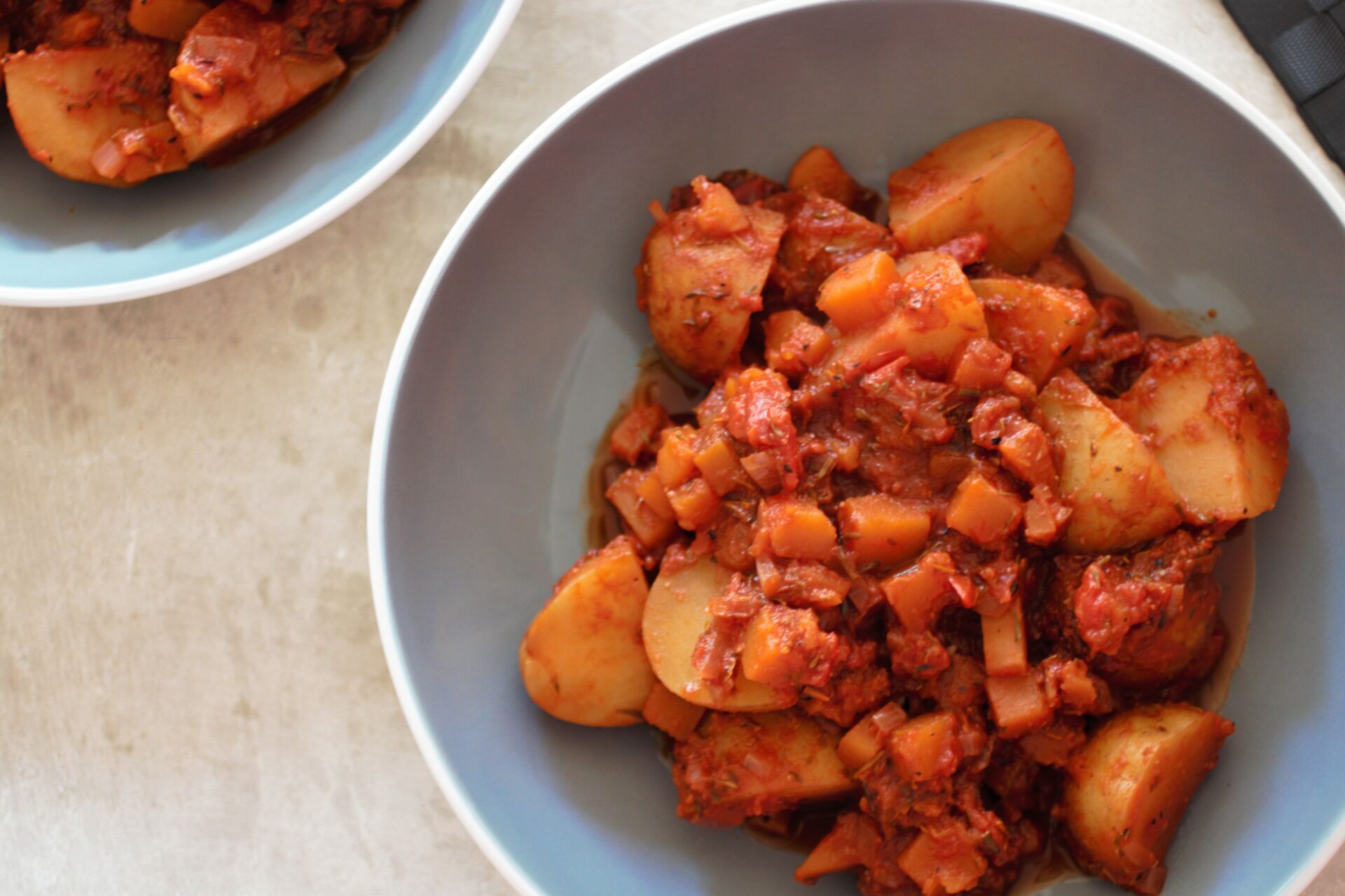 bowl of red wine potato casserole against a grey marl background
