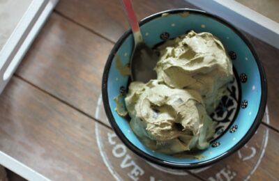 two scoops of soft serve vegan mint chocolate ice cream in a small blue ceramic bowl