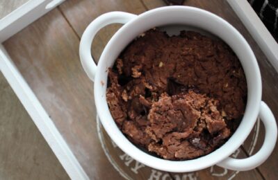 a bowl of mint chocolate baked oats on a grey wooden tray