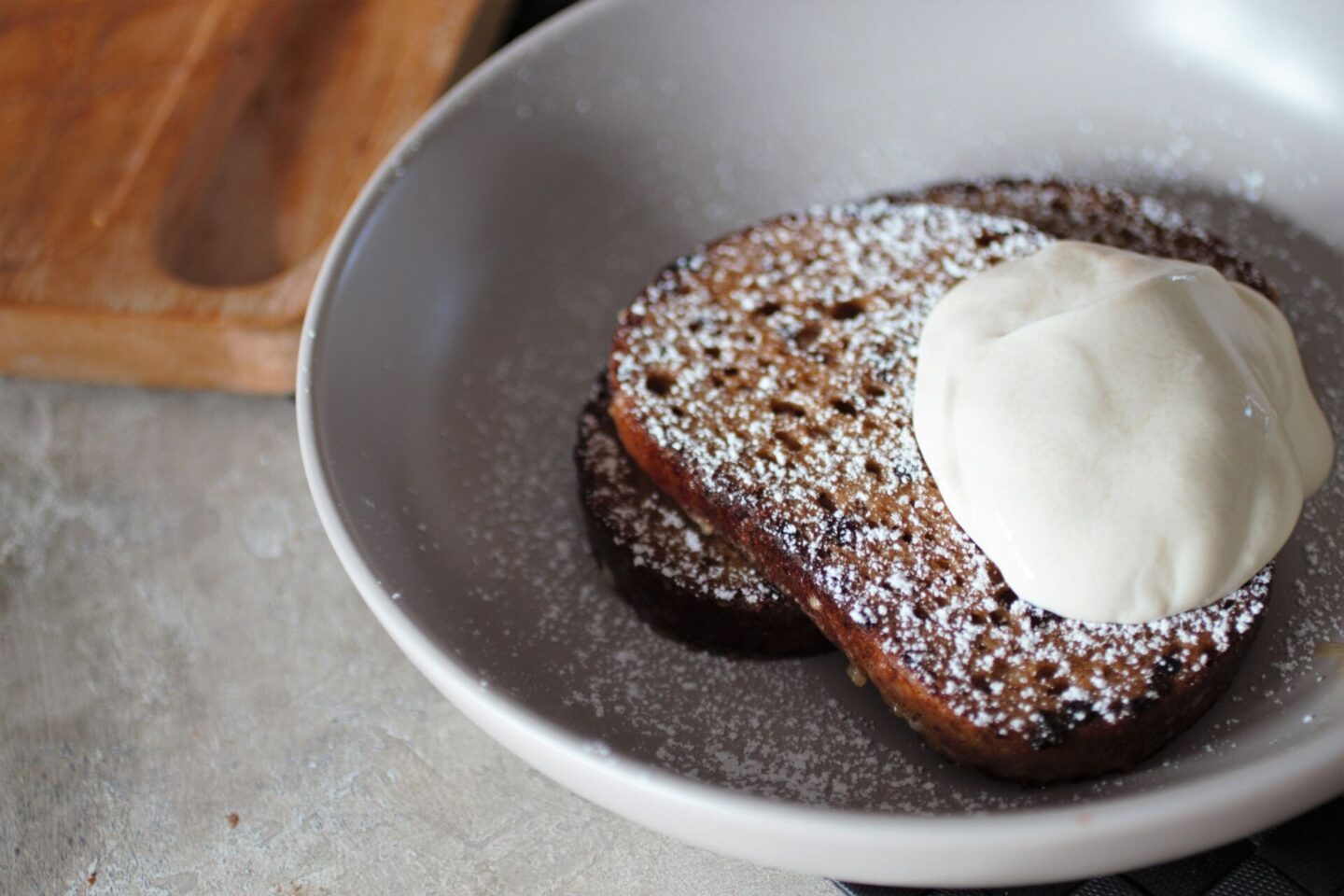 a bowl of orange french toast recipe topped with icing sugar and dairy free yoghurt
