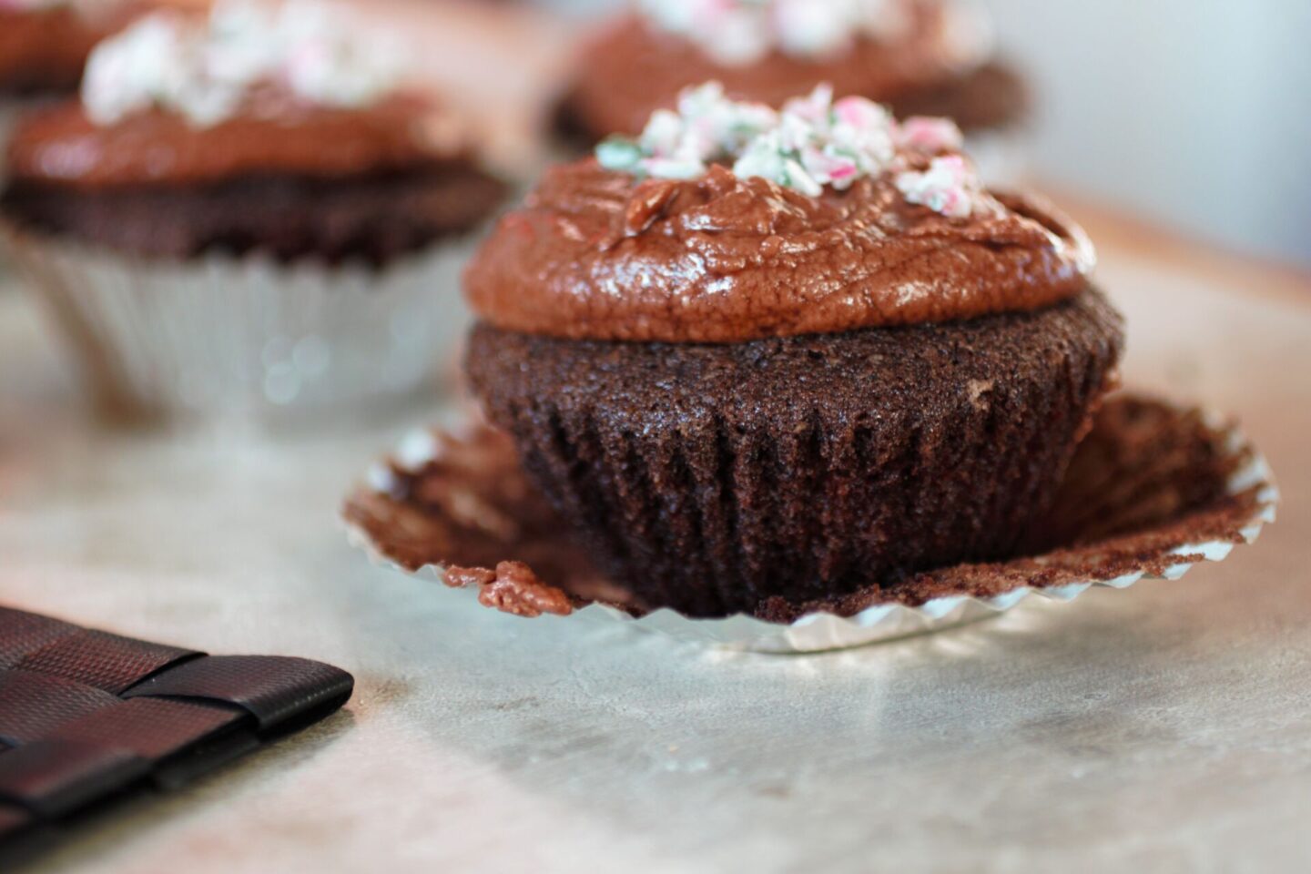 a gluten free vegan chocolate cupcake, shot from the side with the cake case peeled off