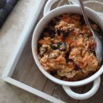 a bowl of carrot cake baked oats in a white bowl with a spoon in