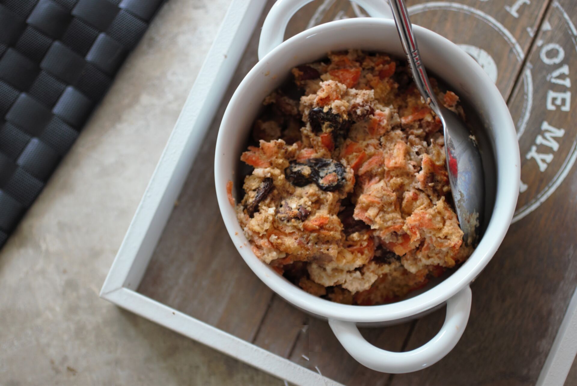 a bowl of carrot cake baked oats in a white bowl with a spoon in