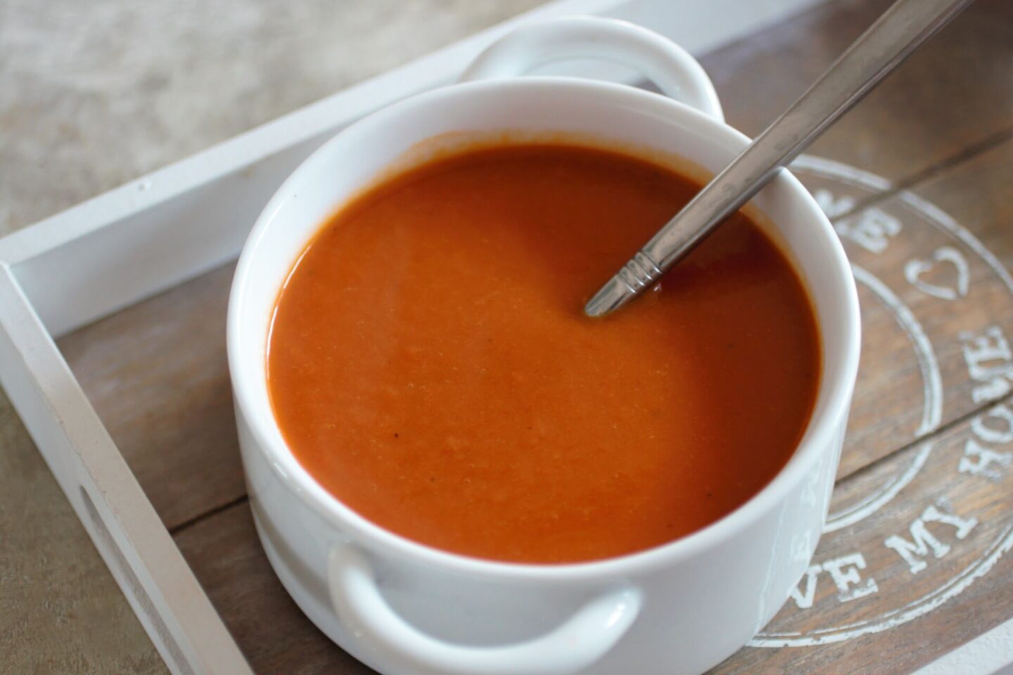 a bowl of carrot & red pepper soup with a spoon in it