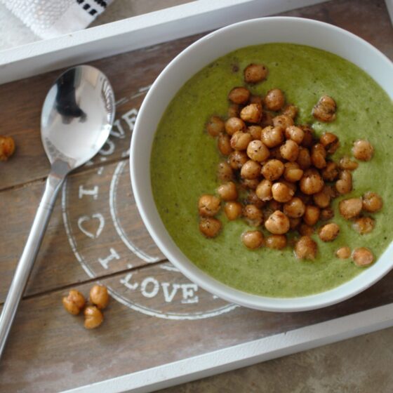 bowl of asparagus & pea soup recipe topped with roasted chickpeas, placed on a wooden tray, shot from above