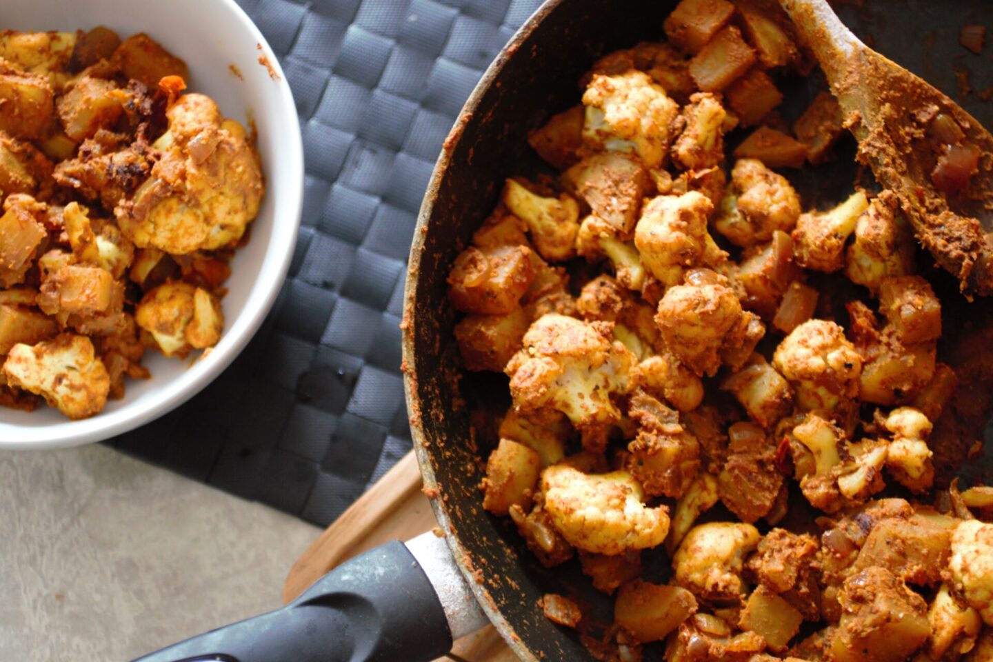 pan of aloo gobi placed next to a bowl of aloo gobi