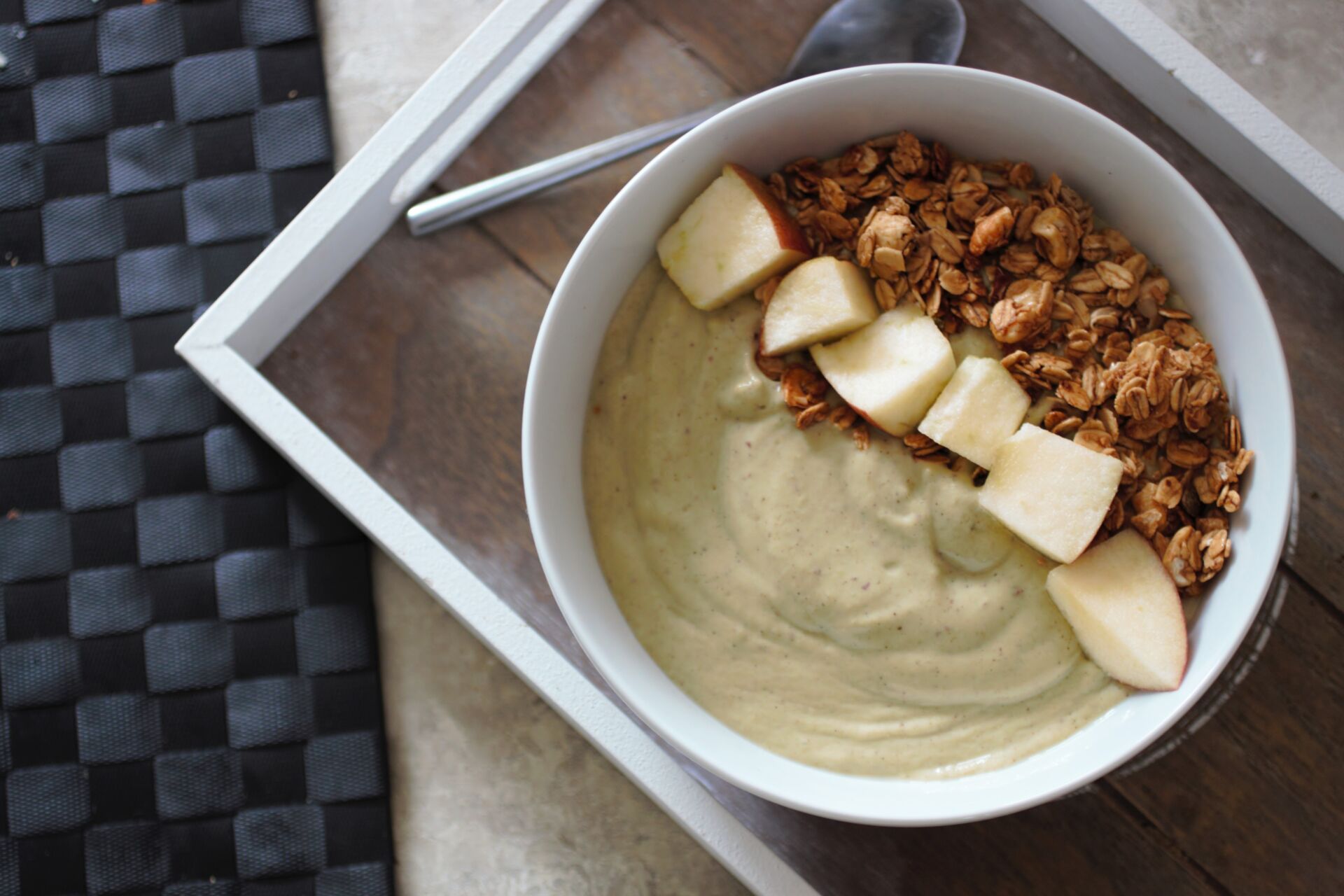 apple pie smoothie bowl in a white bowl, topped with fresh apples and granola, shot from above