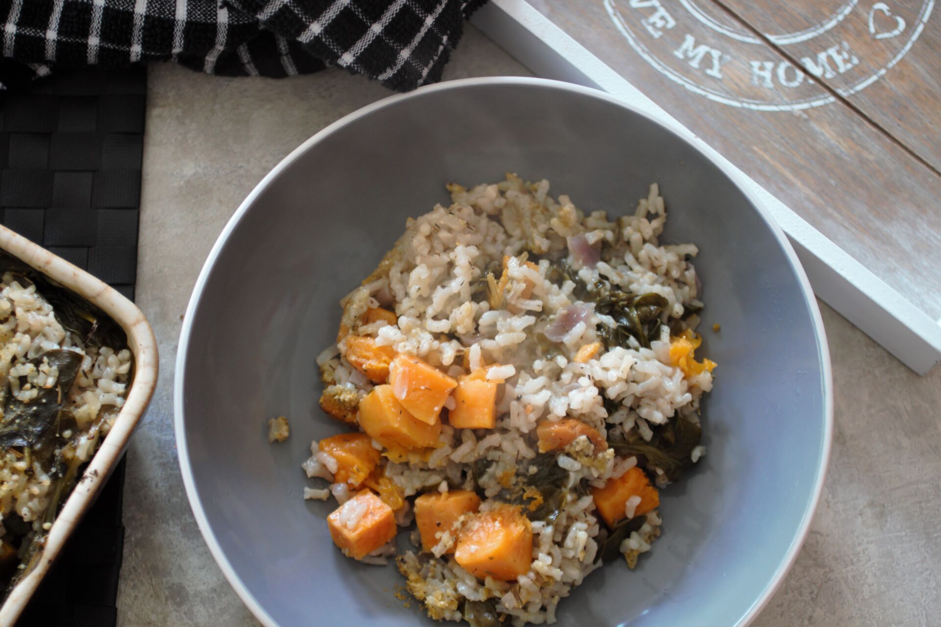 bowl of baked squash risotto next to the baking dish and a grey tray, shot from above