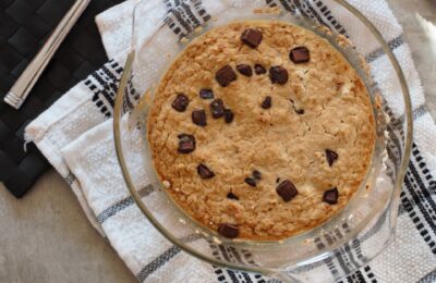 dish of freshly baked basic baked oats recipe, in a ceramic dish, placed on a black and white checked tea towel