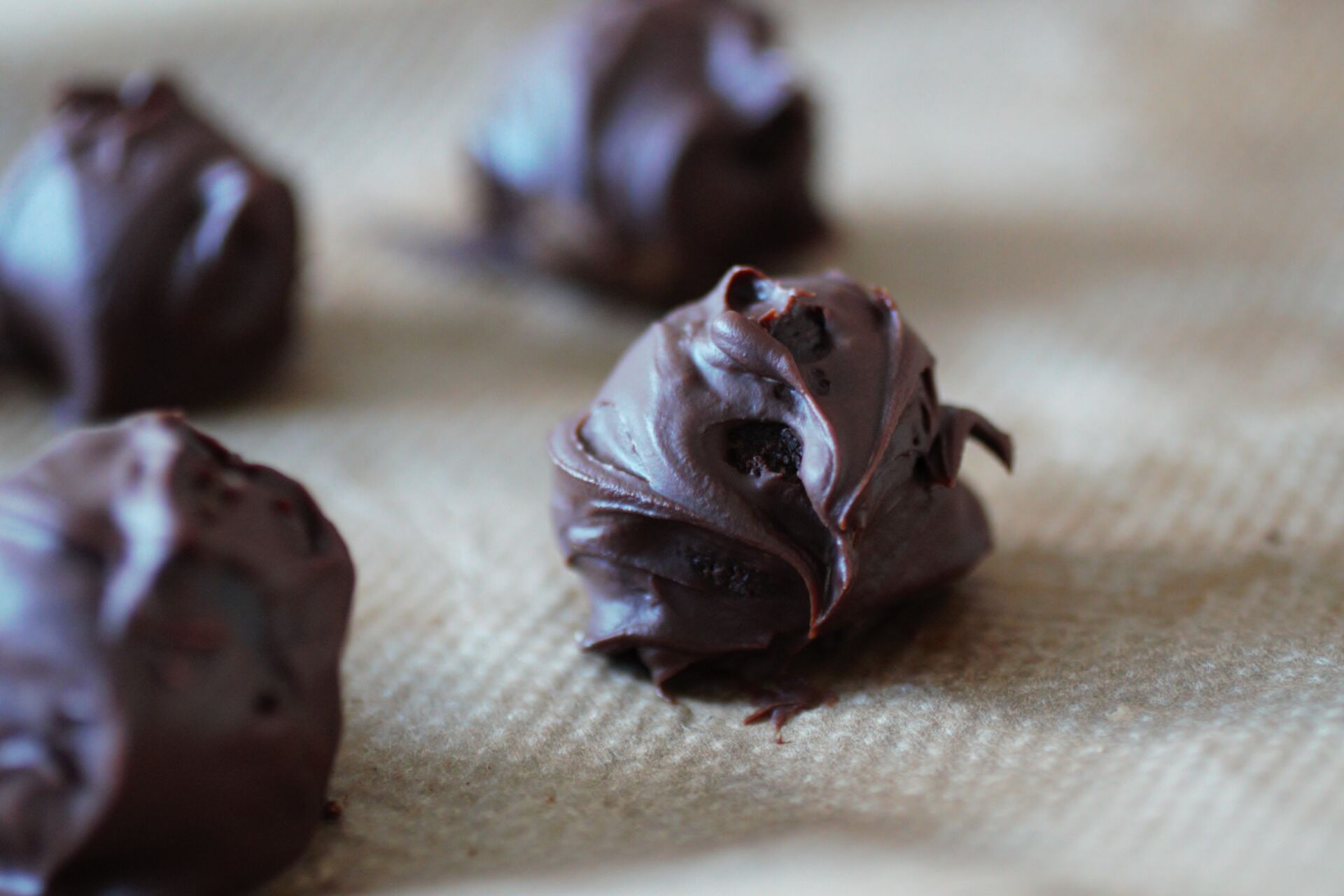 a close up of one vegan chocolate truffle on a sheet of baking paper