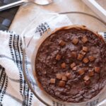 freshly baked chocolate cheesecake baked oats, placed on a tea towel, shot from above