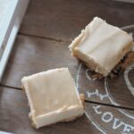 a grey wooden tray with two cookie dough cheesecake squares on it, shot from above