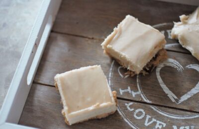 a grey wooden tray with two cookie dough cheesecake squares on it, shot from above