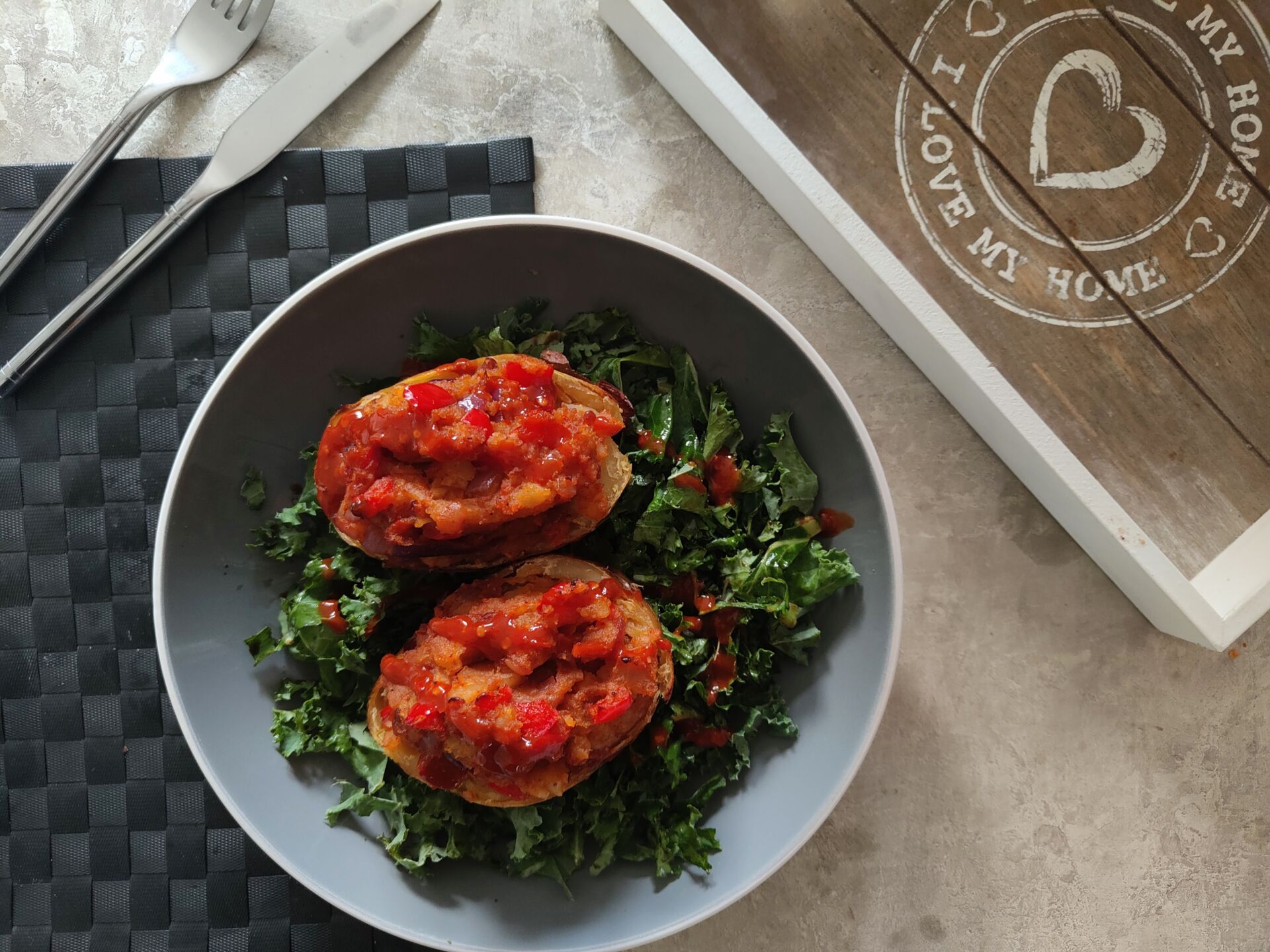 harissa jacket potato in a bowl with kale salad, placed on a table