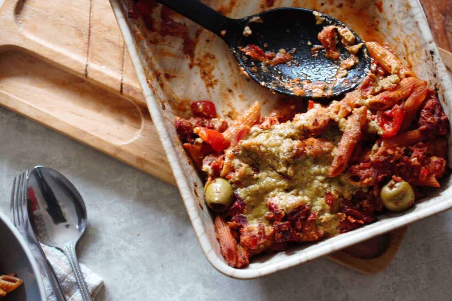 pasta bake dish with serving spoon in it and one serving remaining