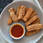 a bowl of tofu fingers with a pot of dip