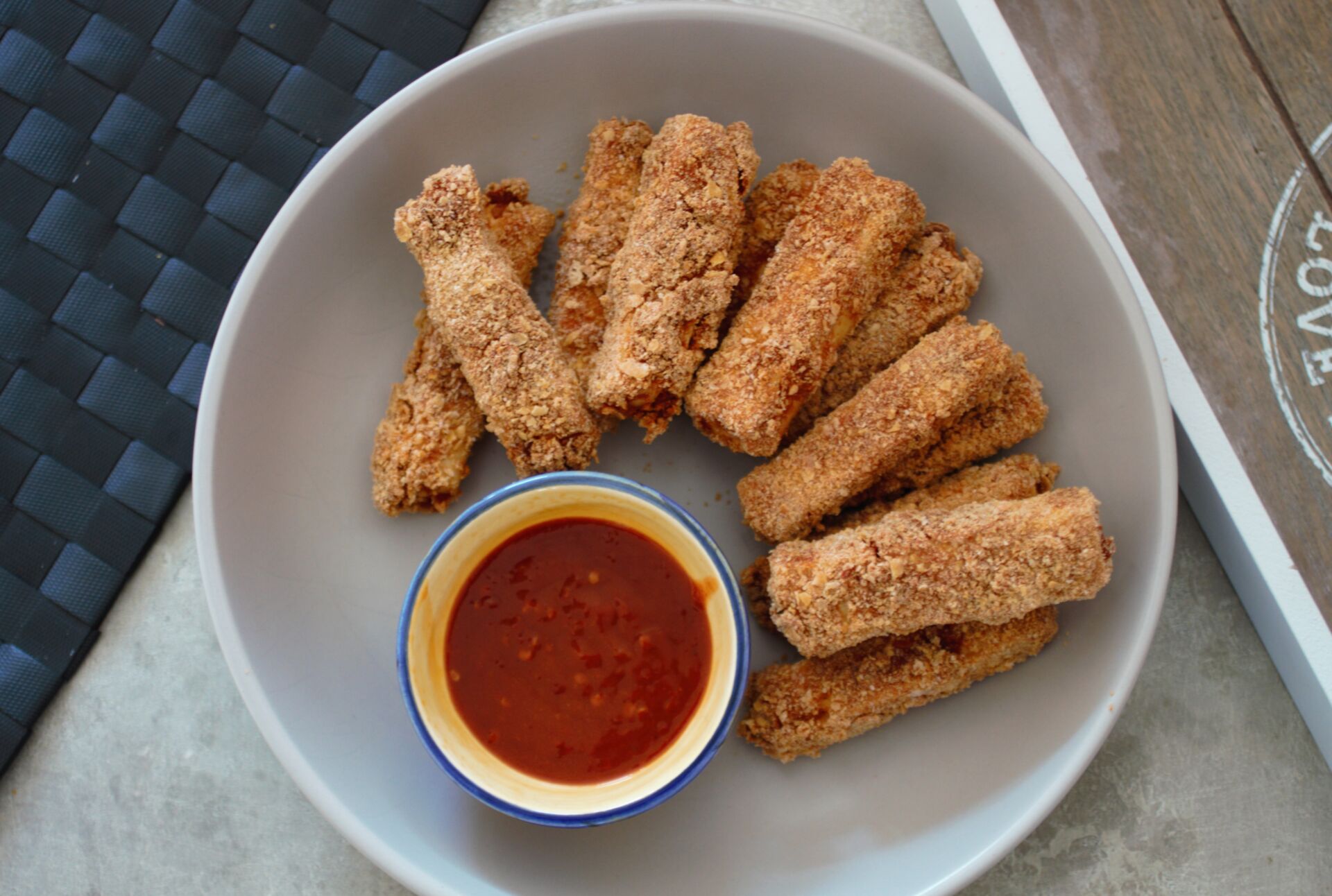 a bowl of tofu fingers with a pot of dip