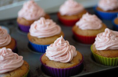 a tray of strawberry cupcakes topped with vegan strawberry frosting