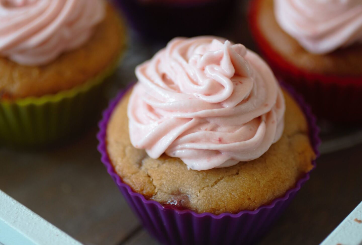 a close up shot of a cupcake topped with vegan strawberry frosting