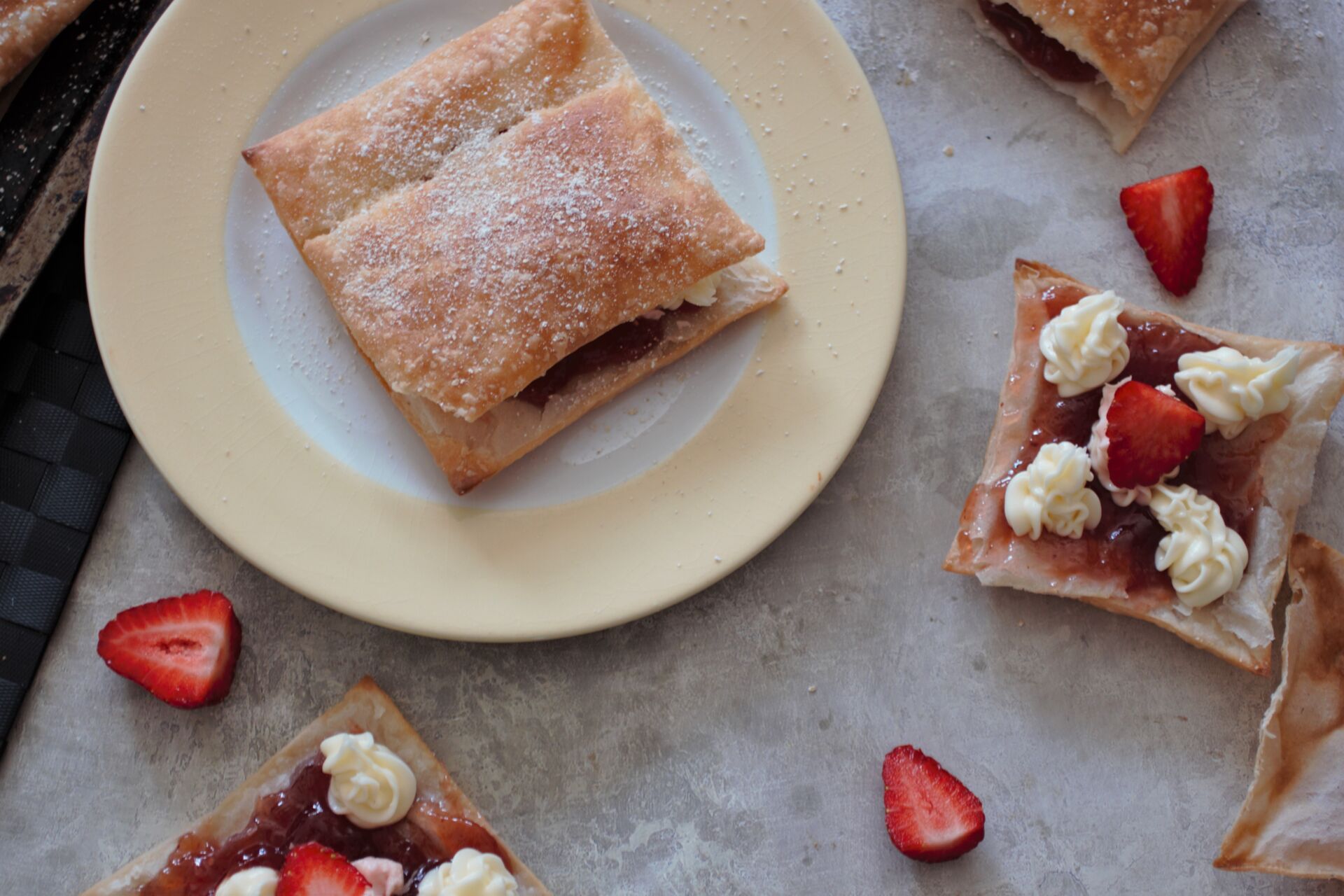 a strawberry cream puff on a plate with some others half assembled scattered around it