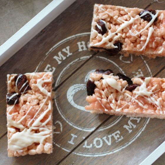 a grey wooden tray with strawberry white chocolate rice krispy treats on it