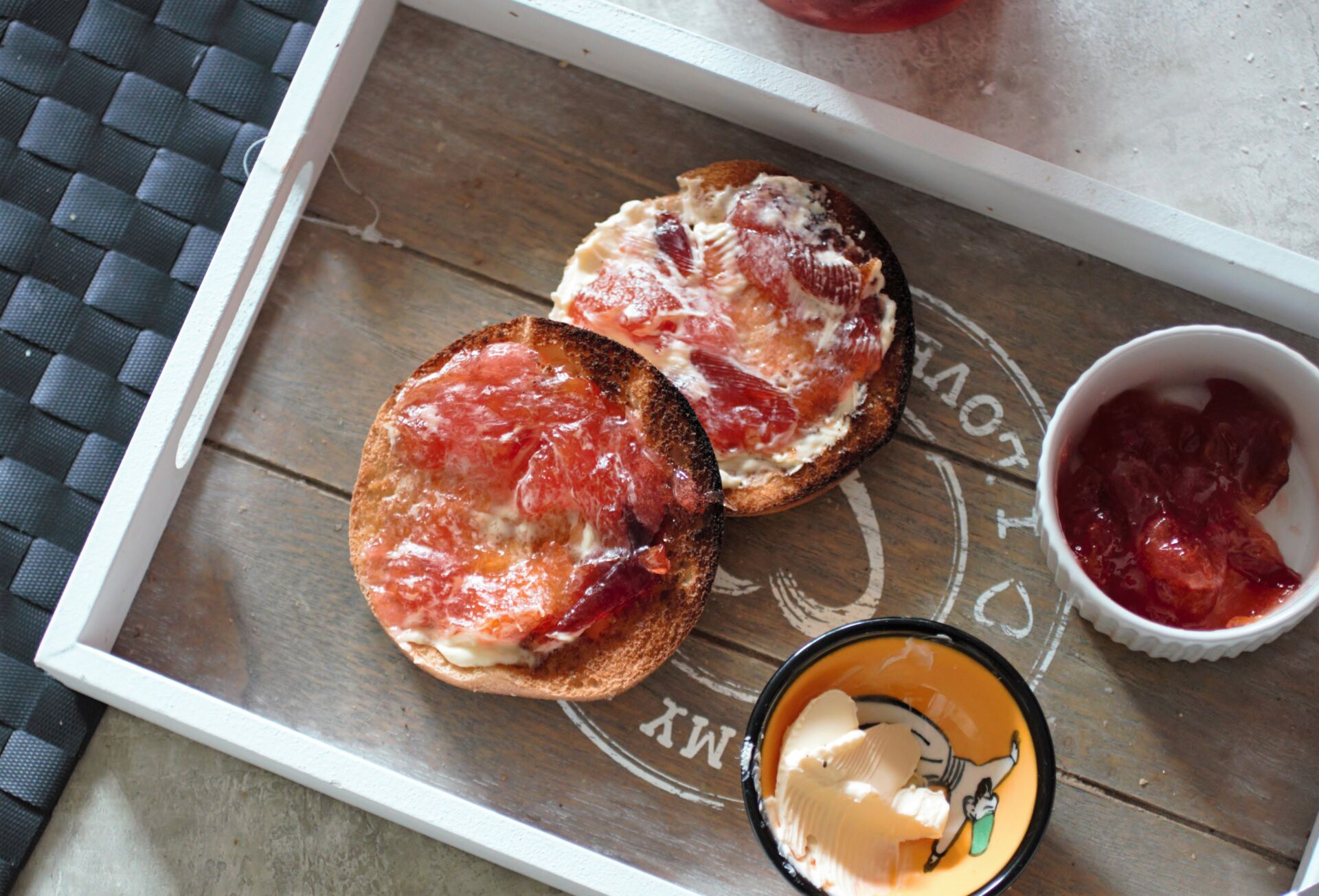 a muffin topped with peach jam next to a pot of simple peach jam recipe