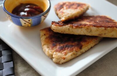 three crispy potato scones on a white plate, shot from the side