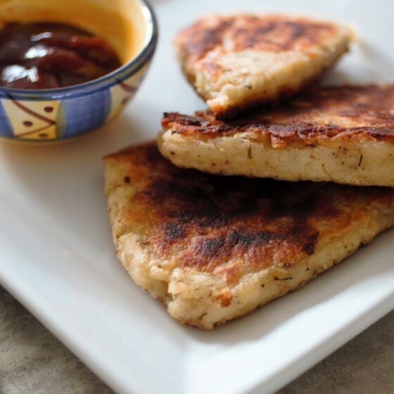 three crispy potato scones on a white plate, shot from the side